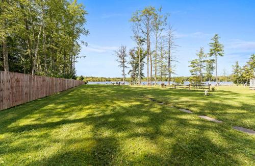 a large grass field with trees and a fence at Eagle's Nest - Lakefront Oasis with Dock Canoe and Fire Pit in Grand Junction
