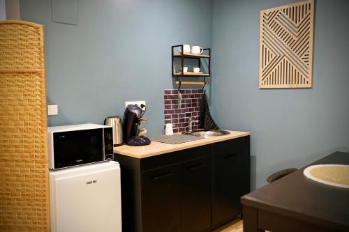 a small kitchen with a sink and a microwave at Suite, Hammam, Sauna, et Jacuzzi in Sedan
