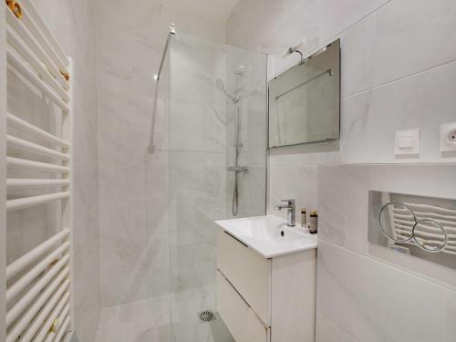 une salle de bain blanche avec une douche et un lavabo dans l'établissement Magnificent apartment - 2BR 6P - Rochechouart, à Paris