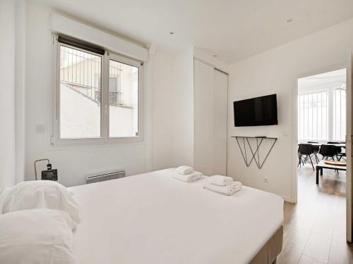 - une chambre blanche avec un grand lit et une télévision dans l'établissement Magnificent apartment - 2BR 6P - Rochechouart, à Paris