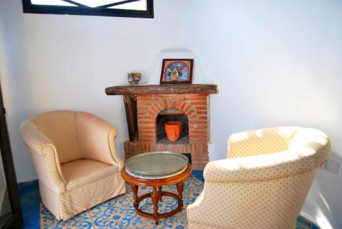 a living room with two chairs and a fireplace at Dar terrae plus in Chefchaouene