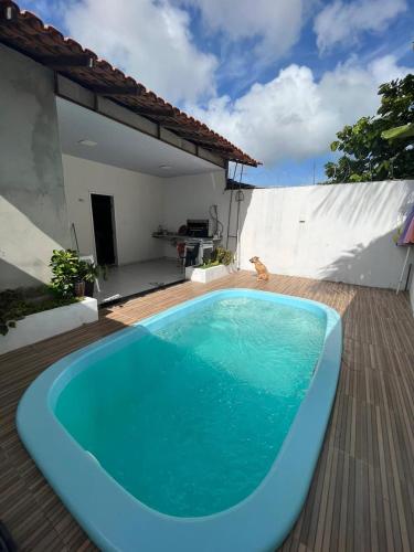 a blue swimming pool on a wooden deck with a house at Casa Salinopolis in Salinópolis
