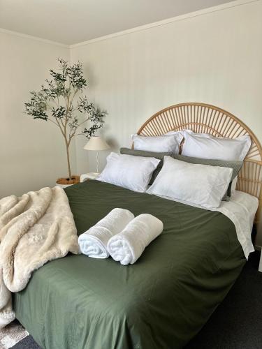 a large green bed with two white pillows on it at Cosy 3 Bedroom Home near airport with free parking in Auckland