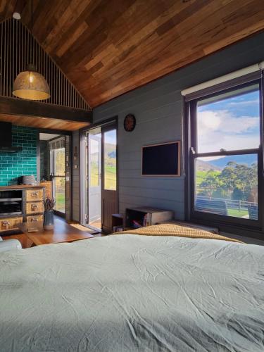 a bedroom with a large bed and a large window at Appledore - Cabin in the Valley in Glen Huon