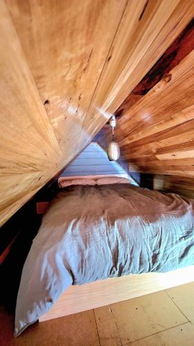 a bed in a room with a wooden ceiling at Appledore - Cabin in the Valley in Glen Huon