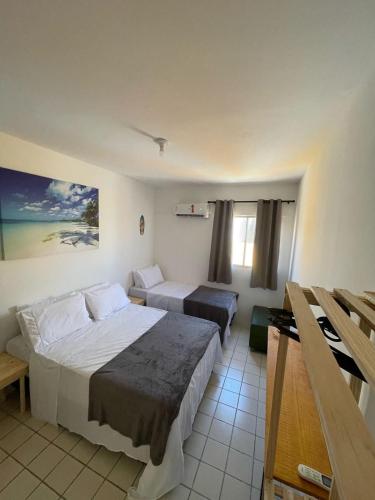 Una habitación de hotel con dos camas y una ventana. en Flat Barra Beach, en Barra de São Miguel
