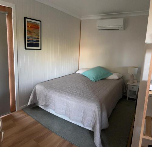 a bedroom with a bed with a green pillow at The Blue House in Lake Tyers