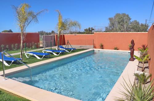 una piscina en un patio con tumbonas azules en Casa Nispero, en Conil de la Frontera
