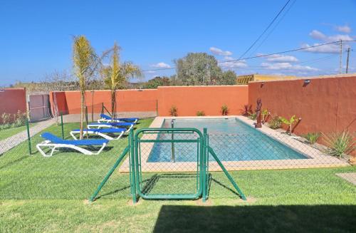 una piscina con 2 sillas y un columpio en Casa Nispero, en Conil de la Frontera