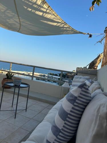 a couch on a balcony with a view of the ocean at KYMA sea view apartment 40 meters from the beach in Makry Gialos