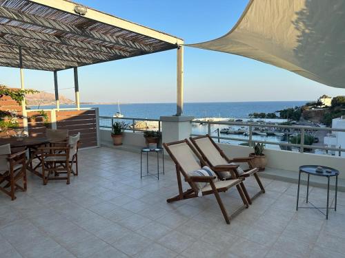 a patio with chairs and a table and the ocean at KYMA sea view apartment 40 meters from the beach in Makry Gialos