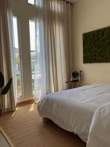 a bedroom with a bed and a large window at Cozy Botanical Garden House in Batam Center