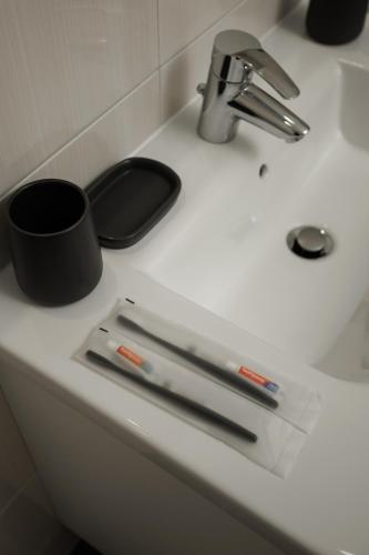 a white bathroom sink with a black mug on it at Dosoftei Residence in Chişinău