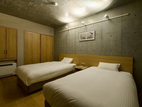 two beds in a small room with two beds sidx sidx sidx at Tabist Kaihorow Otaru in Otaru