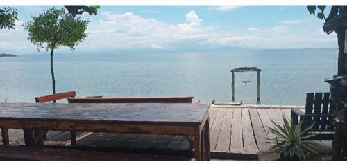 a wooden deck with a table and a view of the ocean at Sunset Moyo Bungalows in Moyo Island