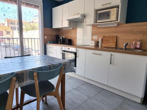 une cuisine avec des armoires blanches et une table avec des chaises dans l'établissement Port-Vendres - Appartement F3 avec parking et WIFI - FR-1-309-241, à Port-Vendres