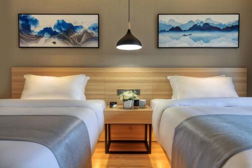 a bedroom with two beds and a table with flowers at Songshe Hotel - Yangshuo West Street in Yangshuo