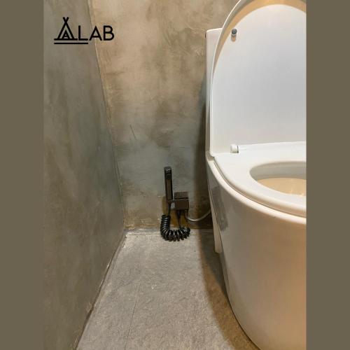 a bathroom with a toilet with a phone next to it at Alab in Mabini