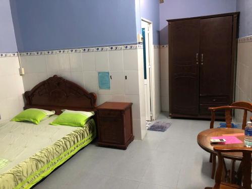 a bedroom with a bed with green pillows and a table at Hong Thanh Hotel Tien Giang in Ấp Nhì (4)