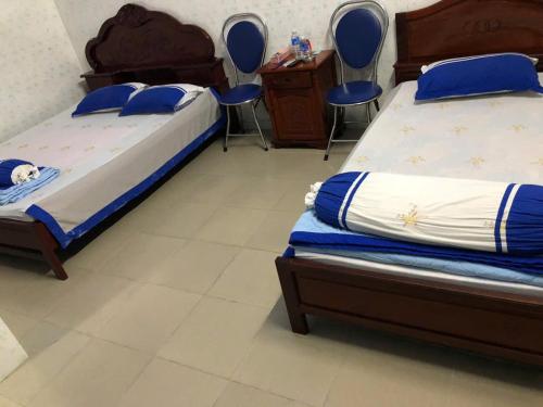 a bedroom with two beds and a desk and chairs at Hong Thanh Hotel Tien Giang in Ấp Nhì (4)