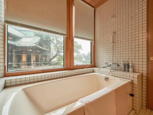 a bath tub in a bathroom with a window at Tabist Kaihorow Otaru in Otaru