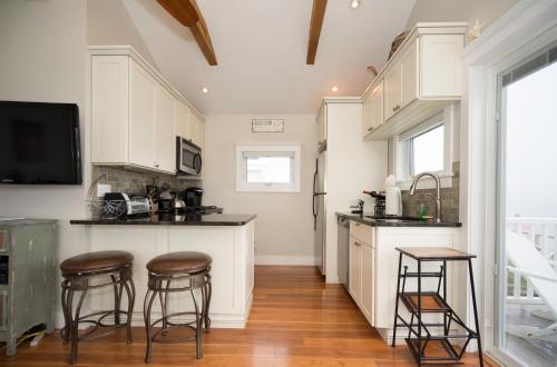 a kitchen with white cabinets and bar stools at The Montauk Soundview in Montauk