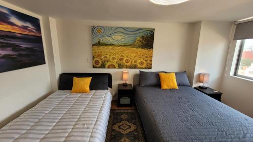 a bedroom with two beds and a painting on the wall at Hermosa Suite doble con baño privado in Mexico City
