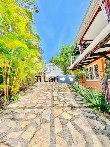 a stone walkway with a sign that reads it left at Ti lari La villa West Indies in Sainte-Luce