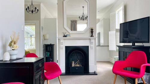 a living room with a fireplace and red chairs at 2 Bedroom Apartment where Modern Luxury meets Historic charm in Wellington