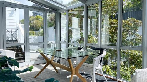a conservatory with a glass table and white chairs at 2 Bedroom Apartment where Modern Luxury meets Historic charm in Wellington