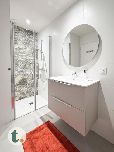 une salle de bain blanche avec un lavabo et un miroir dans l'établissement Tranquiloue - Appartement neuf proche PuyduFou !, aux Herbiers