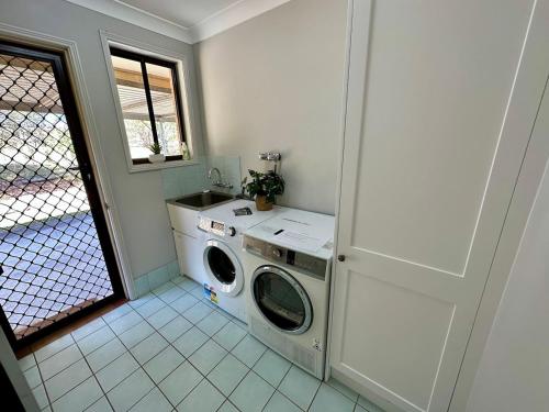 a laundry room with a washing machine and a window at Hunter Valley Homes Pets Heated Pool in Whittingham