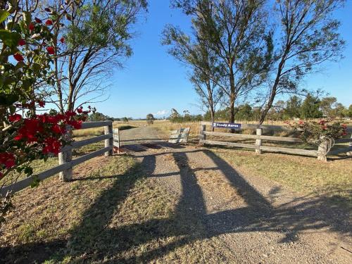 a fence with a bench in front of a field at Hunter Valley Homes Pets Heated Pool in Whittingham