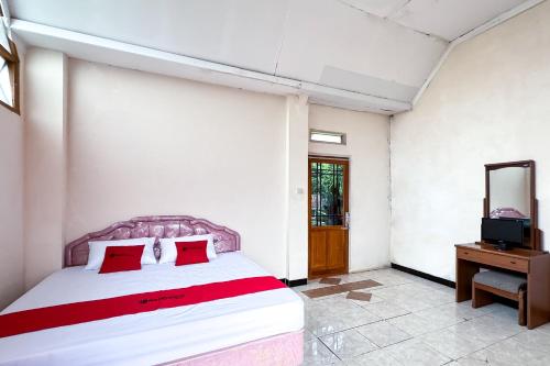 a bedroom with a bed with red pillows and a mirror at RedDoorz at Argapuri Resort Gambung in Gambung