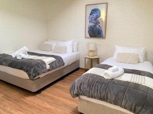 a bedroom with two beds and a picture on the wall at Hunter Valley Homes Pets Heated Pool in Whittingham