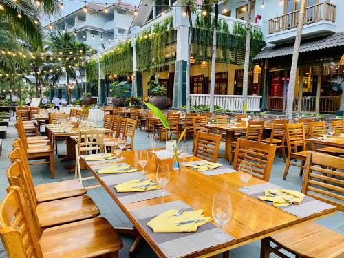 a restaurant with wooden tables and chairs in front of a building at Sonata Resort & Spa in Phan Thiet