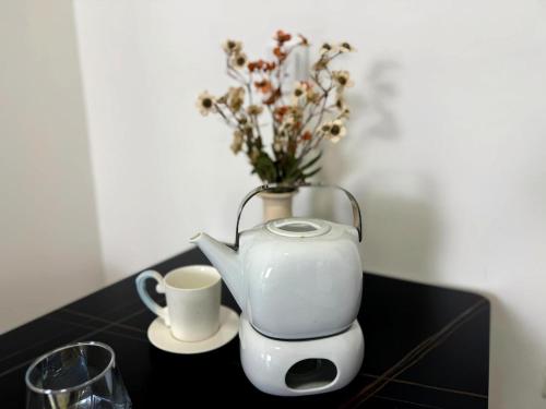 a tea kettle and a vase with flowers on a table at The Ruby - Subang Jaya Edumetro SEGi College in Subang Jaya