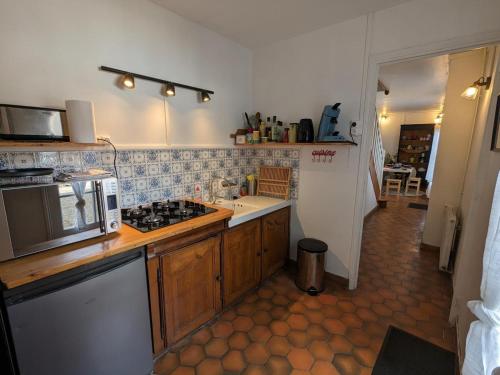 une cuisine avec un évier et une cuisinière four supérieur dans l'établissement Gîte cosy avec jardin clos, terrasse et piscine à proximité, idéal pour famille et détente - FR-1-653-254, à Châteauneuf-sur-Charente