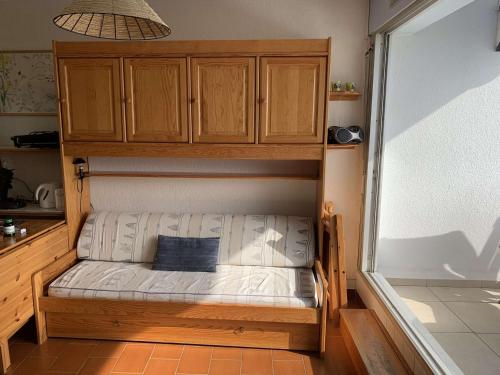 un petit lit dans une chambre avec des armoires en bois dans l'établissement Port Camargue, Appartement 2 Pièces Climat. avec Terrasse Vue Mer - FR-1-731-127, au Grau-du-Roi