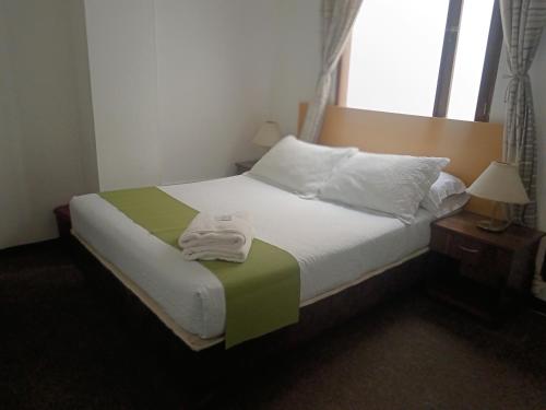 a bedroom with a bed with a towel on it at Hotel del Parque Confort LaCeja in La Ceja