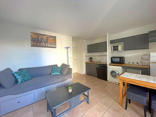 un salon avec un canapé bleu et une cuisine dans l'établissement Appartement 4 pers aux Saintes-Maries-de-la-Mer avec Cour et Parking - FR-1-475-150, à Saintes-Maries-de-la-Mer