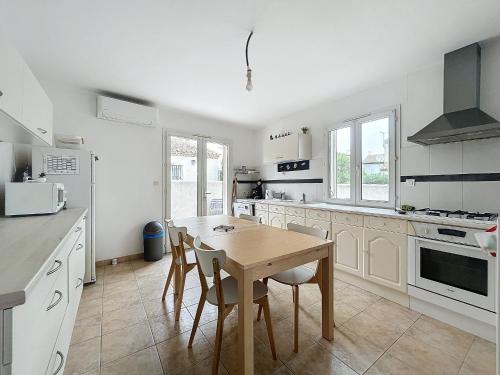 Il comprend une cuisine avec une table et des chaises en bois. dans l'établissement Appartement calme 110m² aux Saintes-Maries-de-la-Mer - FR-1-475-156, à Saintes-Maries-de-la-Mer