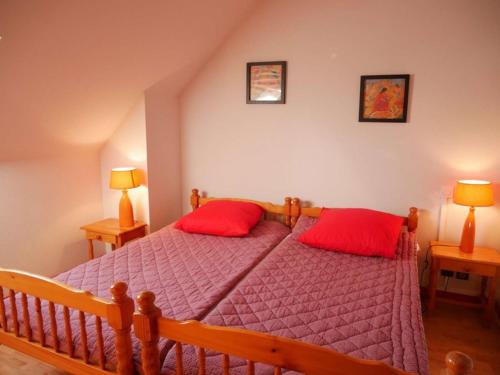 une chambre avec un lit avec deux oreillers rouges dans l'établissement Étel : Appt Duplex 3 Pièces 45m² - Piscine - Animaux Bienvenus - FR-1-479-216, à Étel