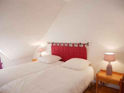 - 2 lits dans une chambre avec une tête de lit rouge dans l'établissement Étel - Appartement 3 pièces - 45 m² - Animaux acceptés - FR-1-479-217, à Étel