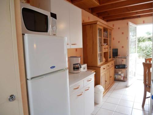 Il comprend une cuisine équipée d'un réfrigérateur blanc et d'un four micro-ondes. dans l'établissement Maisonnette Erdeven 3 pièces, proche plage, parking - FR-1-479-219, à Erdeven