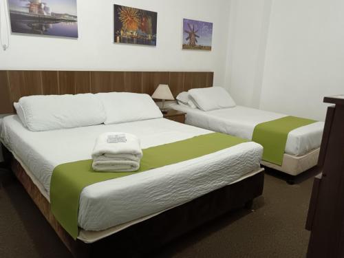 two beds with green and white sheets in a room at Hotel del Parque Confort LaCeja in La Ceja