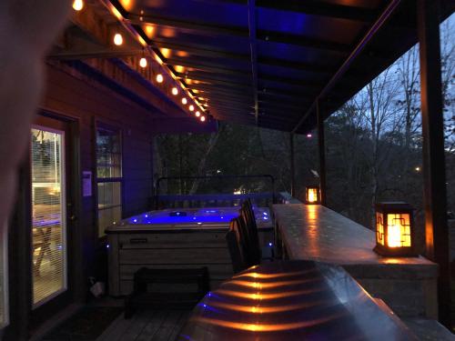 a patio with a hot tub on a deck at night at Majestic Poolside Lookout in Pigeon Forge