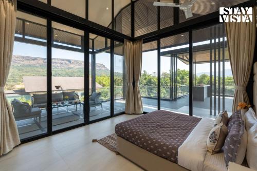 a bedroom with large glass windows and a bed at StayVista at The Nest at Canary Farms - Pool, Lawn in Āmbavna