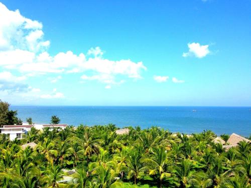 a view of the ocean from a resort with palm trees at Sonata Resort & Spa in Phan Thiet