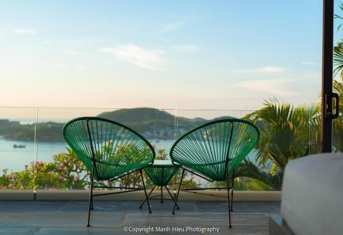 two green chairs sitting on top of a balcony at Ocean View Luxury Retreat - Private Villa by Nest Group in Nha Trang